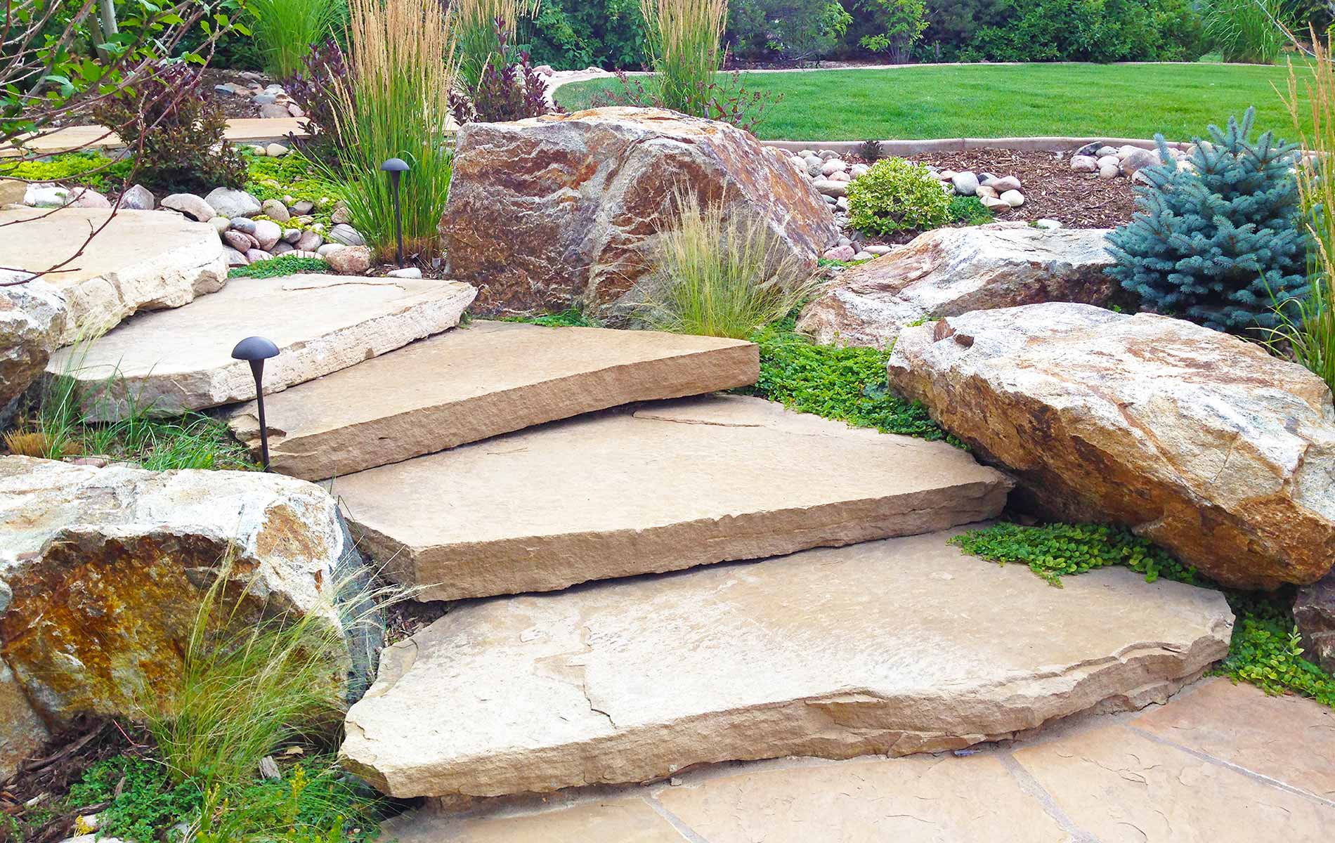 Twisting stone stairs and large boulders in Rustic Outdoor Living in Arvada Mile High Landscaping in Denver