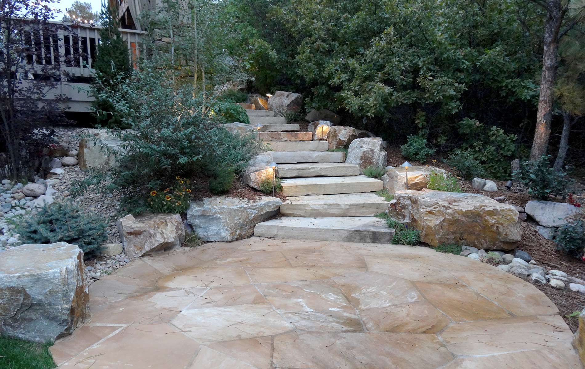 Custom Slab staircase leading to irregular flagstone patio with accent boulders